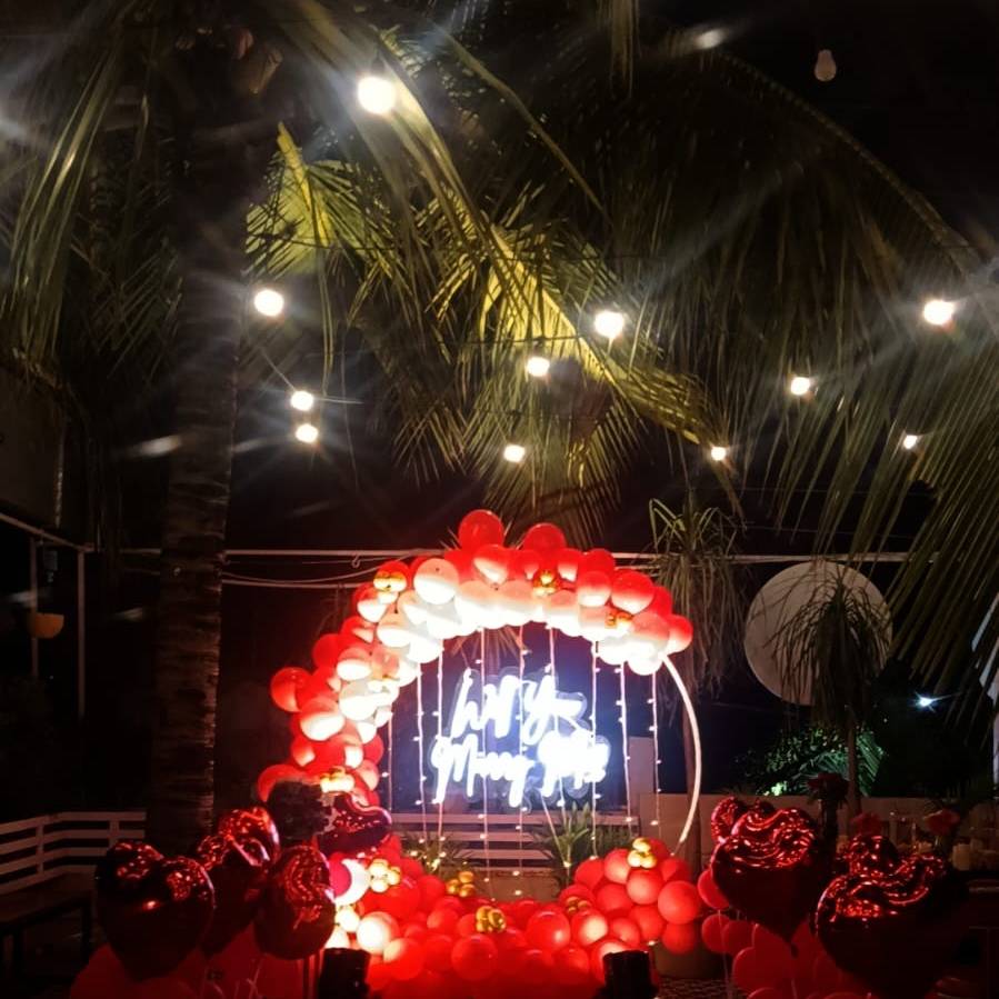 A festive night scene featuring a balloon arch in red and white, with a glowing neon sign surrounded by heart-shaped balloons.