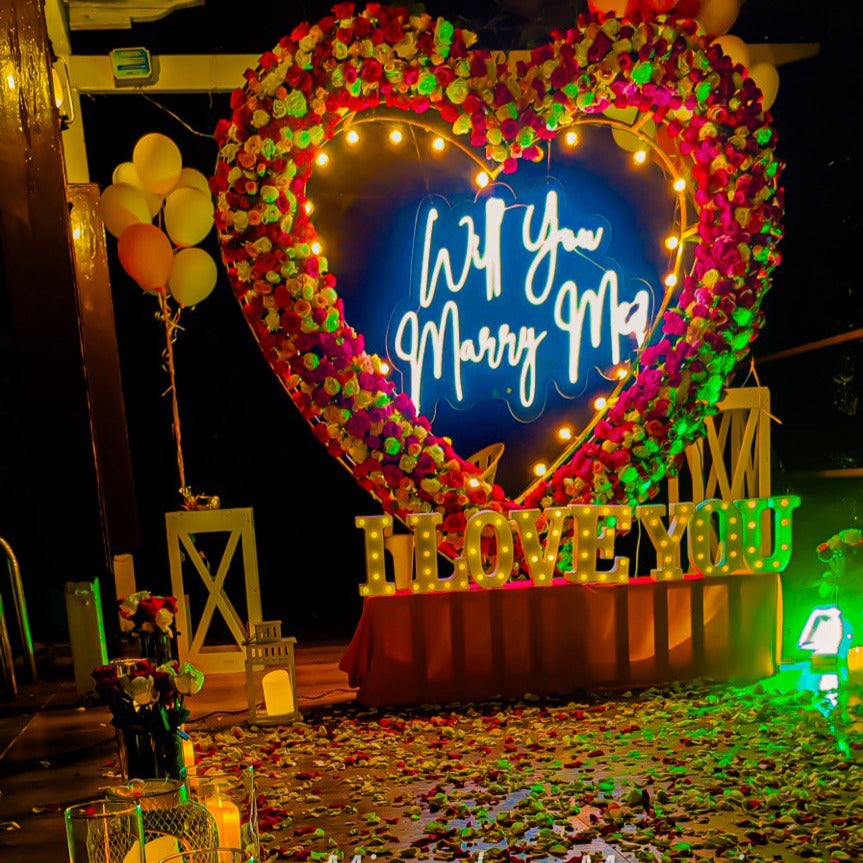 Anniversary celebration in Hyderabad featuring a romantic candle light dinner setup with a personal butler and neon lights.