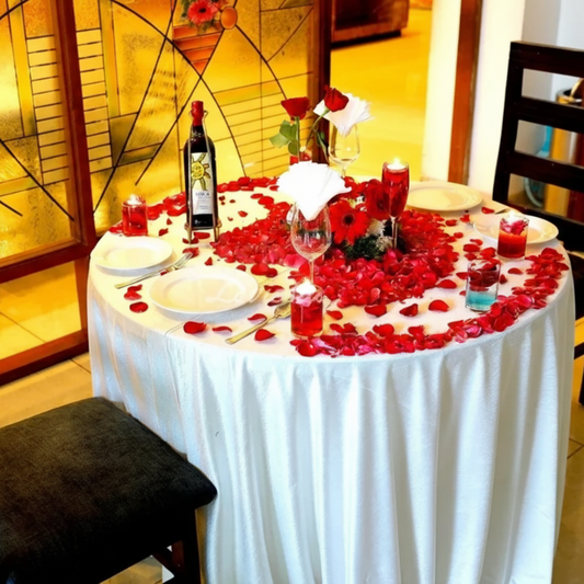 Valentines Day Candle Light Dinner Dining table set for a romantic dinner with rose petals and candles, in a cozy indoor setting.