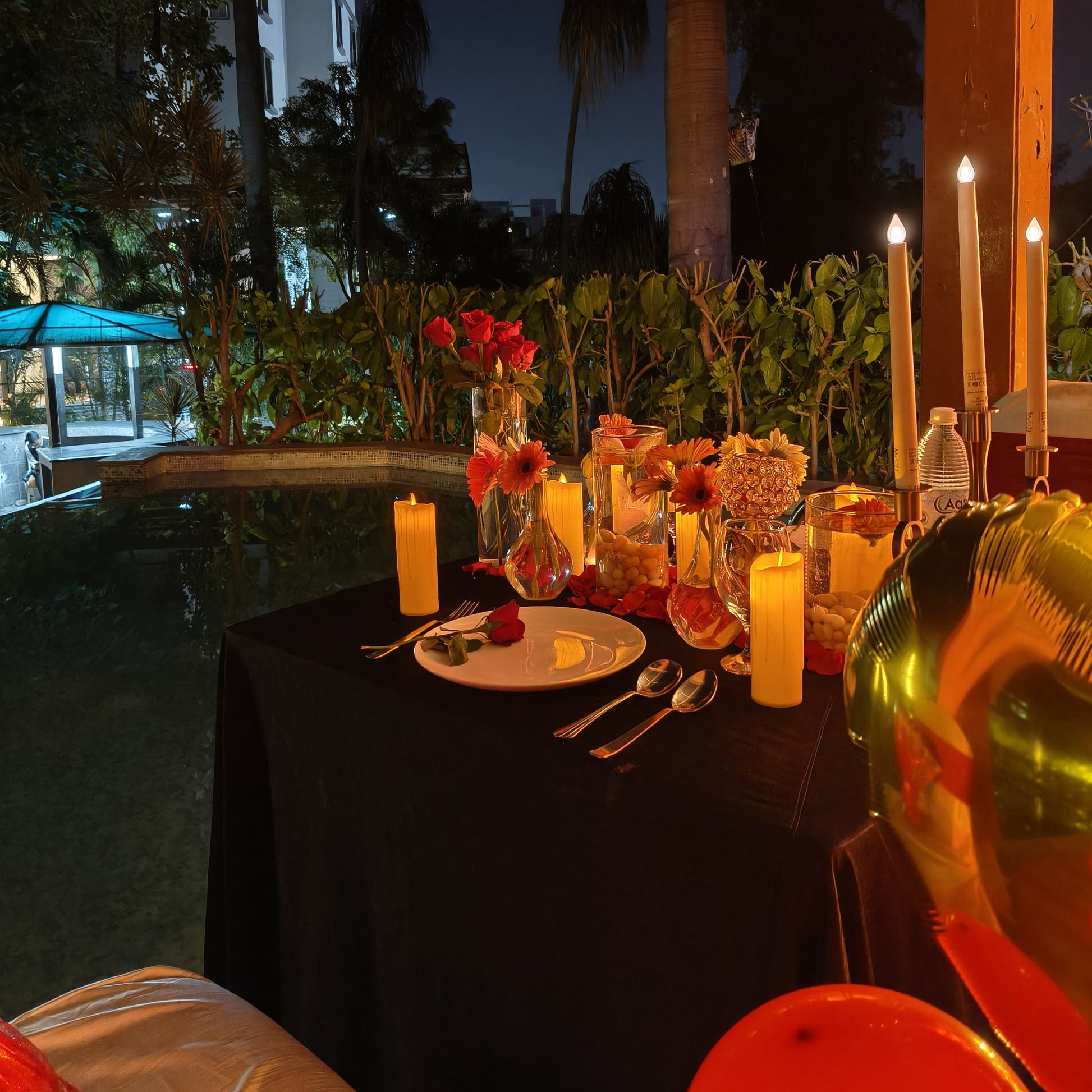 Candle Light Dinner Set up at poolside with red and black theme with romantic ambience to have a romantic dinner at poolside in Hyderabad 