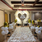 A romantic proposal setup featuring a heart-shaped balloon arch, white flower petals, and golden balloons, with a sign that reads "Will You Marry Me?"