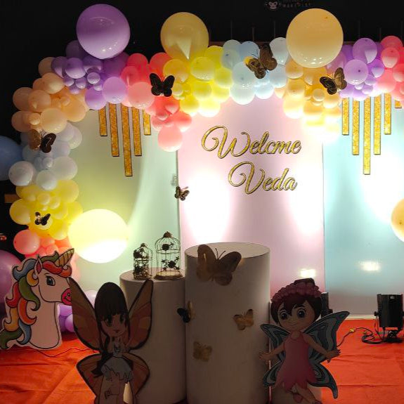 Fairyland pastel theme birthday decoration with unicorn, bunny, reindeer, and fairy cutouts under rainbow balloon arch