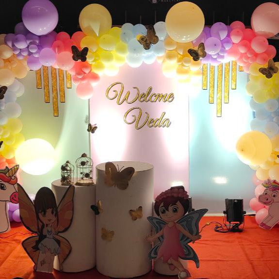 Unicorn and fairyland theme pastel balloon arch decoration with colorful backdrop and character cutouts for kids birthday party in Hyderabad