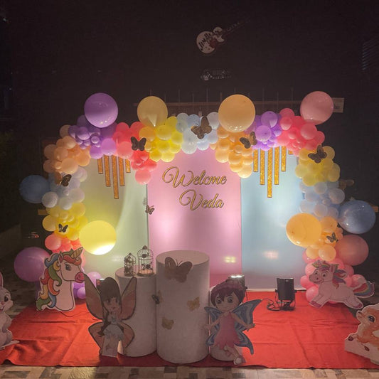 Fairyland unicorn pastel birthday decoration with rainbow balloons, unicorn cutout, fairy cutouts, and Welcome Veda backdrop in Hyderabad